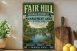 a vintage-style sign for the "Fair Hill Natural Resources Management Area" in Maryland, with a scenic illustration of a lake, trees, and a bird. The sign also includes the text "Conserve, Protect, Enjoy" and " Maryland" at the bottom.
