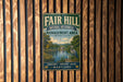 a vintage metal sign with a scenic landscape, mounted on a wooden wall.