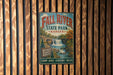 A vintage metal sign for Fall River State Park in Kansas, featuring a scenic image of a waterfall surrounded by trees.