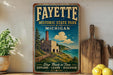 a vintage-style sign for Fayette Historic State Park in Michigan, with a scenic illustration of a building and a lake. The sign is placed on a shelf next to a wooden cutting board and a potted plant.