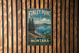 A vintage-style metal sign for Finley Point State Park in Montana, featuring a scenic landscape with mountains, a lake, and pine trees.