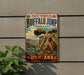 A vintage-style metal sign for Buffalo Jump State Park in Montana, featuring an illustration of buffalo and Native American imagery.