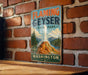 A vintage-style metal sign for Flaming Geyser State Park in Washington, featuring a scenic illustration of the geyser and surrounding landscape.
