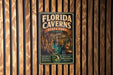 A vintage metal sign for Florida Caves State Park, featuring an illustration of the cave system and the text "FLORIDA CAVENS" and "EXPLORE NATURE'S WONDER".