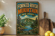 a vintage-style sign for the Forked River Mountain in New Jersey, with a scenic mountain landscape and a river. The sign is displayed on a shelf next to a wooden cutting board and some lemons.