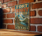 A vintage-style metal sign for Fort Boggby State Park in Texas, featuring a scenic illustration of the park's landscape.