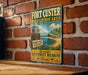 A vintage-style sign for the Fort Custer Recreation Area in South West Michigan, featuring a beach scene and a lighthouse.