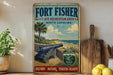 A vintage-style metal sign for Fort Fisher State Recreation Area in North Carolina, featuring a cannon, palm trees, and a beach scene.