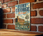 A vintage-style sign for Fort George Island, Florida, featuring a castle and palm trees, mounted on a brick wall.