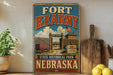 A vintage-style sign for Fort Kearny, a State Historical Park in Nebraska, featuring an illustration of a wooden wagon and a sign that reads "1848 ON THE PORT".