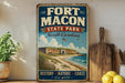 A vintage-style sign for Fort Macon State Park in North Carolina, featuring an illustration of the fort and beach.