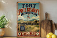 A vintage-style metal sign for Fort Phil Kearny, a historic site in Wyoming, with a picture of the site and a flag.