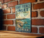 A vintage-style metal sign for Fort Pierce Inlet State Park in Florida, featuring a lighthouse and a beach scene.