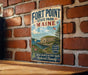 A vintage metal sign for Fort Point State Park in Maine, featuring a scenic illustration of the park and its surroundings.
