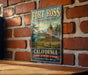 A vintage-style metal sign for Fort Ross, a historic park in California, featuring a scenic illustration of a building and landscape.