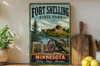 A vintage-style sign for Fort Snelling State Park in Minnesota, featuring a cannon, a stone wall, and a scenic landscape.