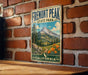 A vintage metal sign for Fremont Peak State Park in California, featuring a mountain landscape with pine trees, flowers, and a trail.