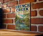 A vintage-style metal sign for French Creek State Park in Pennsylvania, featuring a scenic illustration of a river, bridge, and wildlife.