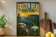 A vintage-style poster of Frozen Head State Park, featuring a scenic mountain landscape with pine trees and a sunset in the background.