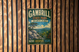 A vintage metal sign for Gambrill State Park, Maryland, featuring a scenic mountain landscape with a pine tree and rocky outcropping.
