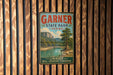 A vintage metal sign for Garnier State Park in Texas, featuring a scenic landscape with a river and mountains.