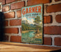 A vintage-style metal sign for Garner State Park in Texas, featuring a scenic landscape with a river, mountains, and trees.