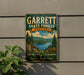 A vintage metal sign for Garrett State Forest, Maryland, featuring a scenic landscape with pine trees, a lake, and mountains.