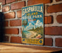 A vintage-style metal sign for Gasparilla Island State Park in Florida, featuring a beach scene with palm trees, a lighthouse, and a seashell.
