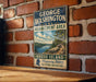 A vintage metal sign for the George Washington Management Area in Rhode Island, featuring a scenic landscape with a river and mountains.