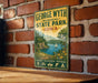 A vintage-style metal sign for George Wyth Memorial State Park in Iowa, featuring a scenic landscape with a lake, mountains, and a sailboat.