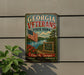 A vintage-style metal sign for Georgia Veterans State Park, featuring an American flag, a scenic landscape, and the text "GEORGIA VETERANS STATE PARK" and "Cordele, Georgia EXPLORE, RELAX, REMEMBER".