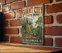 A vintage-style sign for Giant City State Park in Illinois, featuring a scenic image of a rock formation surrounded by trees and mountains.