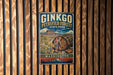 A vintage-style metal sign for Ginkgo Petrified Forest State Park in Washington, featuring a colorful illustration of a petrified tree trunk and a mountain backdrop.