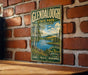 A vintage-style metal sign for Glendalough State Park in Minnesota, featuring a scenic landscape with a lake, trees, and mountains.