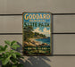 A vintage-style metal sign for Goddard Memorial State Park in Rhode Island, featuring a scenic landscape with a beach, mountains, and a house.