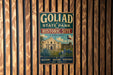 A vintage-style metal sign for Goliad State Park and Historic Site in Texas, featuring a building and a desert landscape.