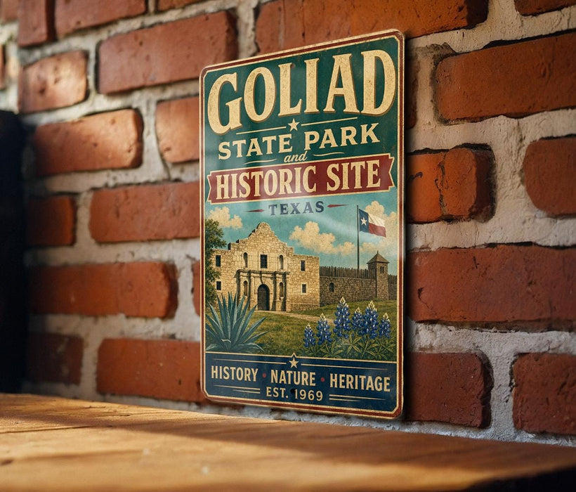 A vintage-style metal sign for Goliad State Park and Historic Site in Texas, featuring an illustration of the historic Alamo and surrounding landscape.