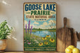 A vintage-style sign for Goose Lake Prairie State Natural Area in Illinois, featuring a scenic landscape with a lake, flowers, and a wooden paddle.
