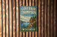 A vintage metal sign for Governor Thompson State Park in Wisconsin, featuring a scenic landscape with a lake and mountains.