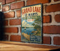 A vintage-style metal sign for Grand Lake State Park in Ohio, featuring a scenic image of a lake with a dock and a sailboat.