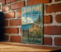 A vintage-style sign for Grass Point State Park in New York, featuring a scenic landscape with a beach, mountains, and pine trees.