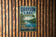 A vintage metal sign for Grayson Lake State Park in Kentucky, featuring a scenic landscape with a lake, mountains, and a boat on the water.