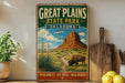 A vintage-style metal sign advertising the Great Plains State Park in Oklahoma, featuring a scenic illustration of a bison grazing in the foreground and a desert landscape with a mountain in the background.