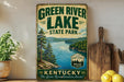 A vintage-style sign for Green River Lake State Park in Kentucky, featuring a scenic illustration of the lake surrounded by mountains and pine trees.