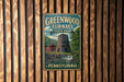 A vintage-style metal sign for Greenwood Furnace State Park in Pennsylvania, featuring a tower and a waterfall.