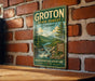 A vintage-style metal sign for Groton State Forest in Vermont, featuring a scenic mountain landscape with a river and pine trees.