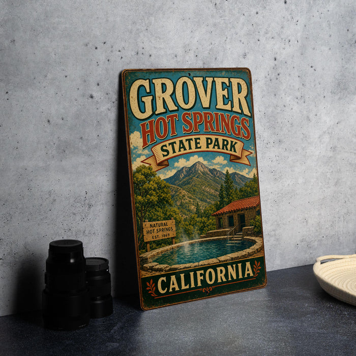 A vintage-style metal sign for Grover Hot Springs State Park in California, featuring a scenic illustration of the park's natural hot springs and surrounding landscape.