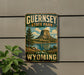 A vintage-style metal sign for Guernsey State Park in Wyoming, featuring a scenic landscape with a mountain, lake, and trees.