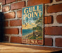 A vintage metal sign for Gull Point State Park in Iowa, featuring a scenic illustration of the park's landscape with a bird flying over the water.