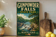 A vintage-style sign for Gunpowder Falls State Park in Maryland, featuring a scenic landscape with a waterfall and forest.